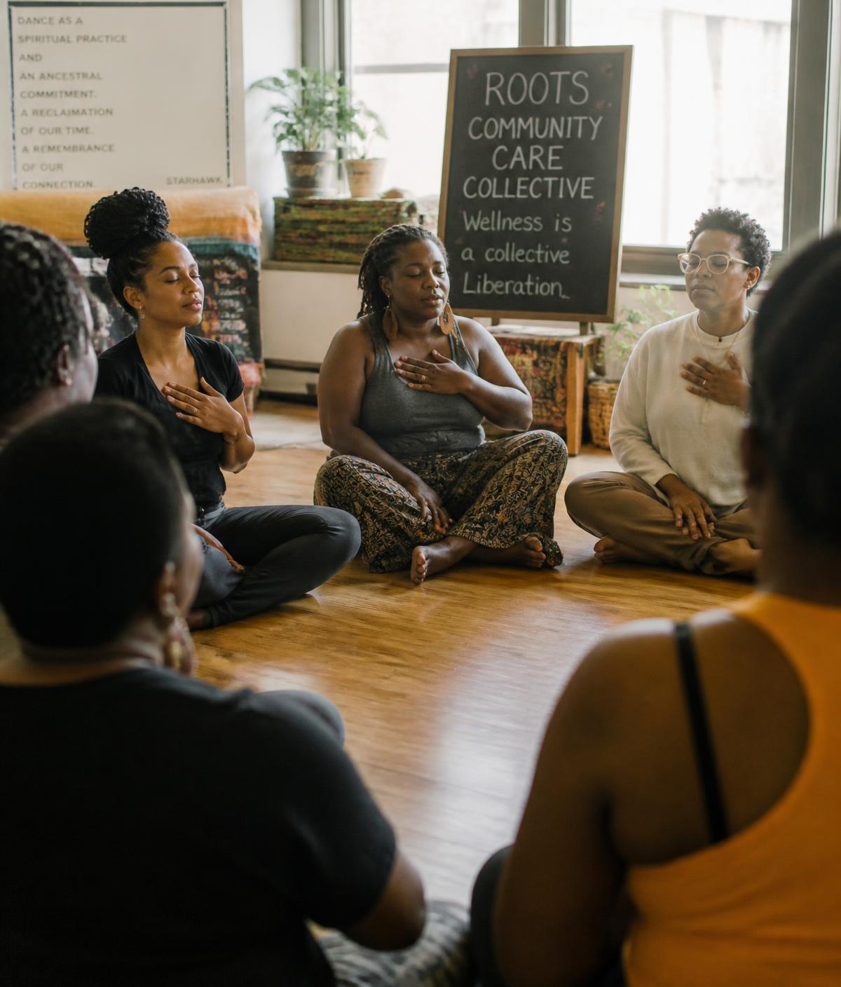 Community members seated in a circle with hands on hearts during a breathwork session